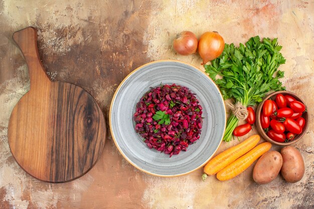 Top view a ceramic plate with homemade delicious salad and ingredients for its preparation on a wooden background with copy space