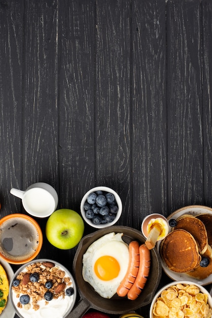 Top view of cereal and yogurt with sausages and egg for breakfast