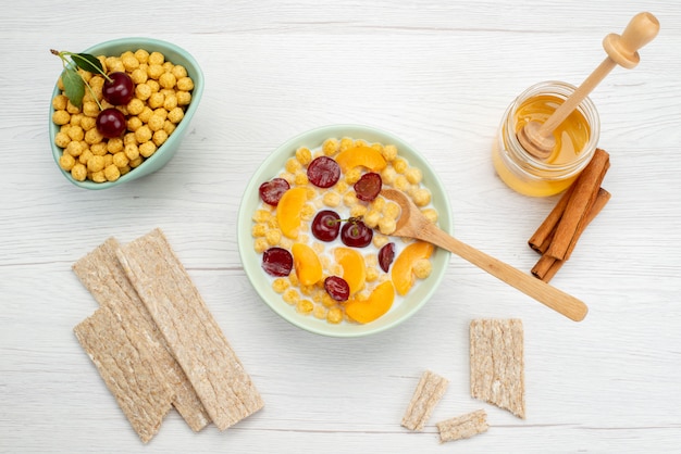 Top view cereals with milk inside plate with crackers and honey on white, drink milk dairy creamery