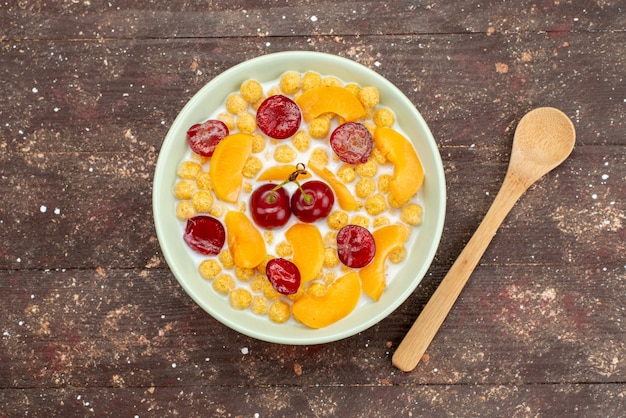 Top view cereals with milk inside plate with fresh fruits on wood, cornflakes cereals breakfast
