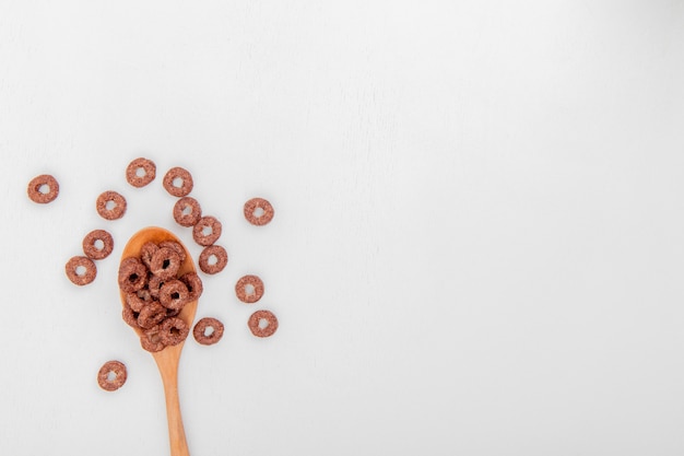 Top view of cereals in wooden spoon on white background with copy space