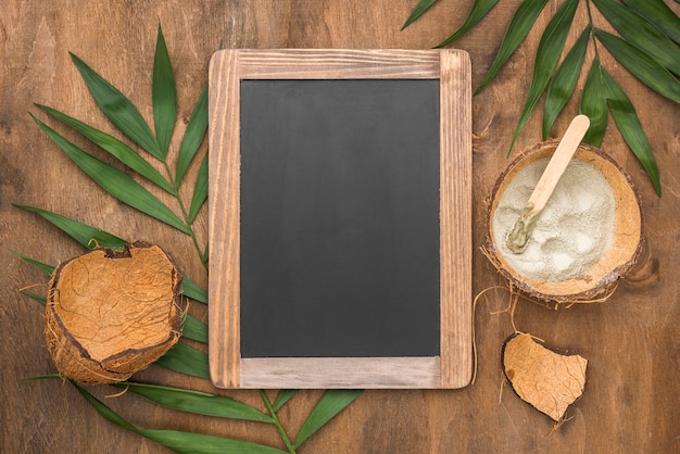 Top view of chalkboard with powder in coconut shell and leaves
