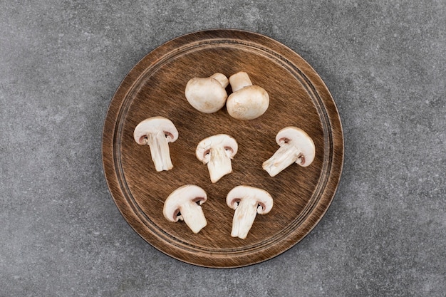 Top view of champignon mushrooms. Chopped or whole on wooden board