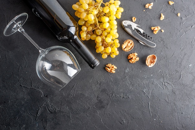 Top view charming yellow grapes wine bottle and glass wine opener walnut on dark table