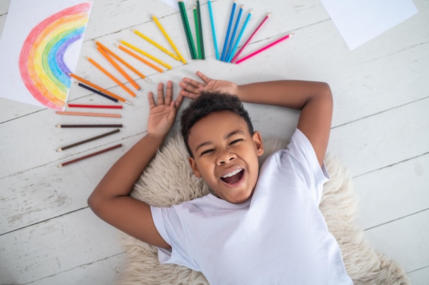 Top view of cheerful boy lying on floor