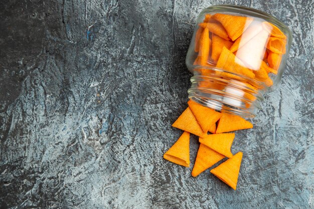 Top view cheese cips inside glass can on a dark surface