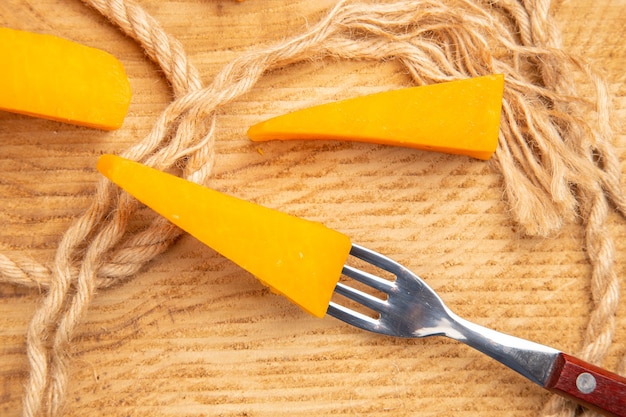 Top view cheese on fork slices of cheese and rope on wooden table