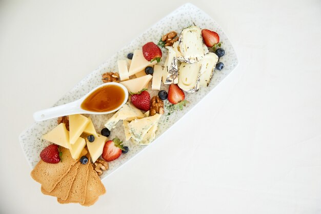 Top view of cheese set with honey, nuts, strawberries and toasts
