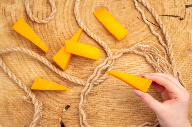Top view cheese slices rope cheese in female hand on wooden table