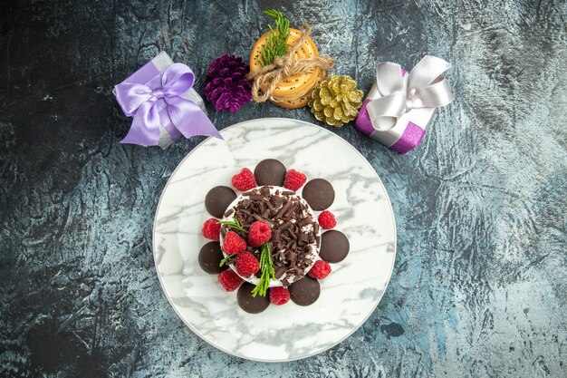 Top view cheesecake with chocolate on oval plate tied cookies xmas ornaments on grey surface