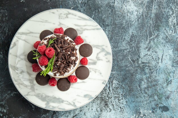 Top view cheesecake with chocolate on white oval plate on grey surface with free space