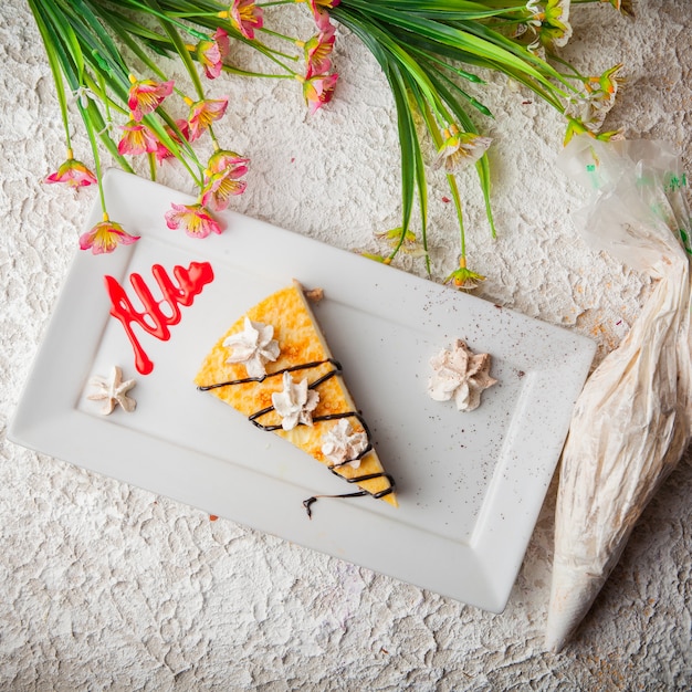 Free photo top view cheesecake with flowers and cream in white plate
