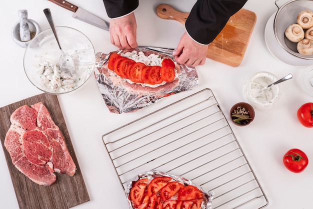 Foto gratuita vista superiore del cuoco unico che prepara piatto con carne e pomodori