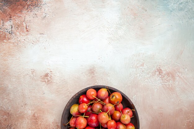 Top view of cherries bowl of the appetizing red-yellow cherries on the table