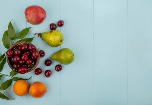 ボウルにさくらんぼの上面図と梨のパターンアプリコット桃のさくらんぼ葉と青い背景にコピースペース