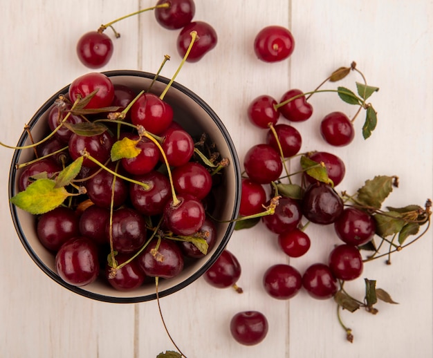 Top view of cherries in bowl and on wooden background