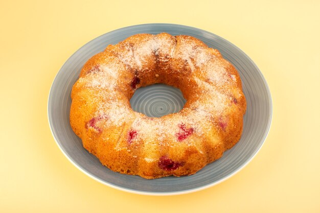 Круглый вишневый торт, вид сверху, сформированный внутри серой тарелки на желтом письменном столе, печенье, сахар, сладкое