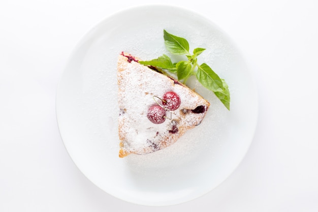 Foto gratuita vista dall'alto fetta di torta di ciliegie deliziosa e gustosa all'interno del piatto bianco su sfondo bianco torta biscotto dolce pasta di zucchero cuocere