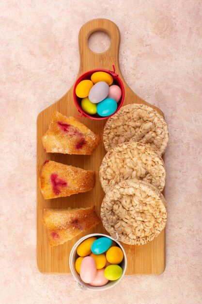 Free photo a top view cherry cake slices with candies and biscuits on the pink table