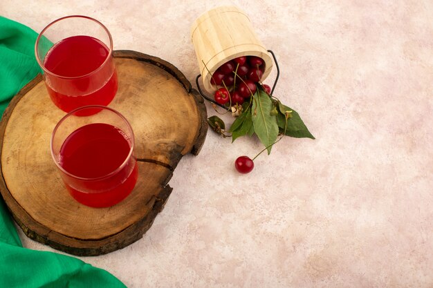 A top view cherry cocktail red inside little glasses fresh cooling along with fresh cherries on pink