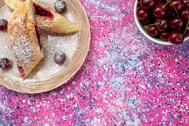 Top view cherry pastry delicious and sweet sliced with fresh sour cherries inside plate on the colored background cake biscuit sugar sweet bake