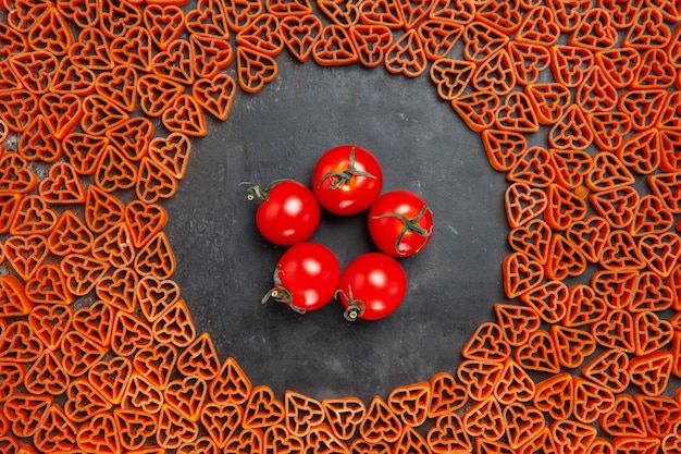 Foto gratuita vista dall'alto pomodorini intorno alla pasta italiana cuore rosso?