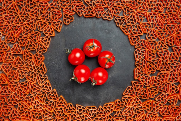 Вид сверху помидоры черри вокруг итальянской пасты с красным сердцем