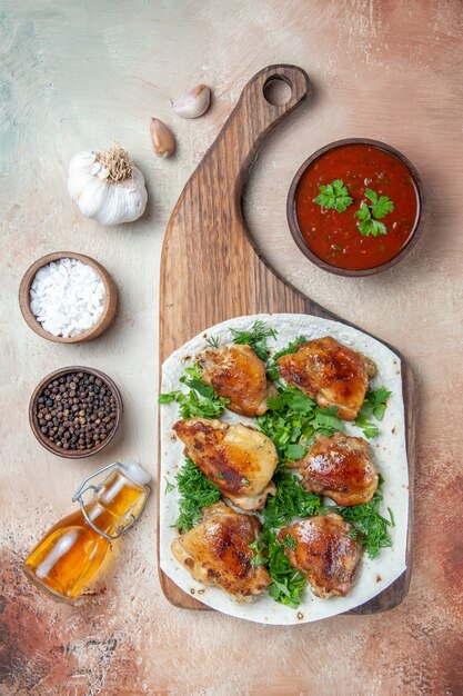 Top view of chicken bowl of sauce spices oil chicken with herbs on lavash on the board