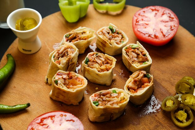 Free photo top view chicken chopped doner in pita bread with hot pepper tomatoes and bell peppers on a stand