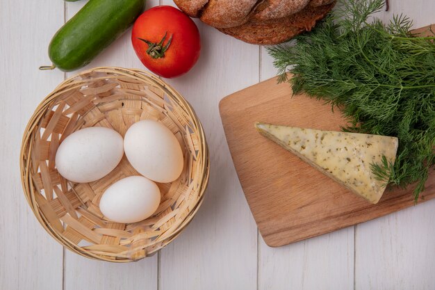 토마토 오이 바구니에 닭고기 달걀과 치즈와 흰색 배경에 딜 검은 빵 한 덩어리