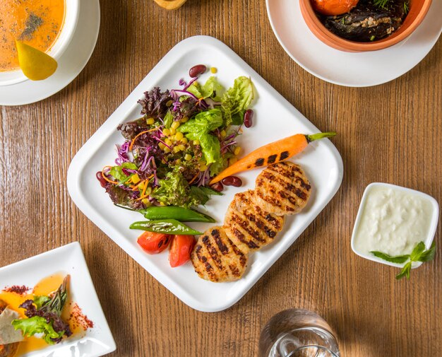 Top view chicken fillet cotlets and salad with yogurt.