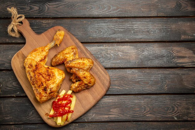 Top view chicken french fries appetizing chicken with french fries and ketchup on the cutting board on the left side of the wooden table