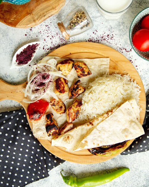 Top view of chicken kebab served with rice flatbread onion and sumac