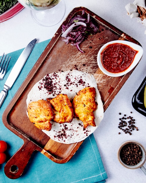 Top view of chicken kebab with red onions on a wooden board