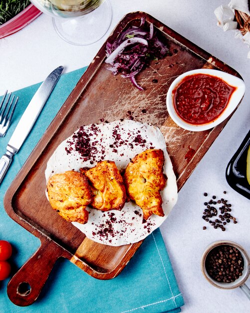 Top view of chicken kebab with red onions on a wooden board