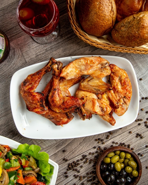 나무 테이블에 와인 한 잔과 함께 접시에 배열 닭 다리와 날개 케밥의 상위 뷰