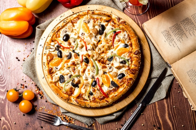 Top view chicken pizza with yellow cherry tomatoes and bell pepper on the board