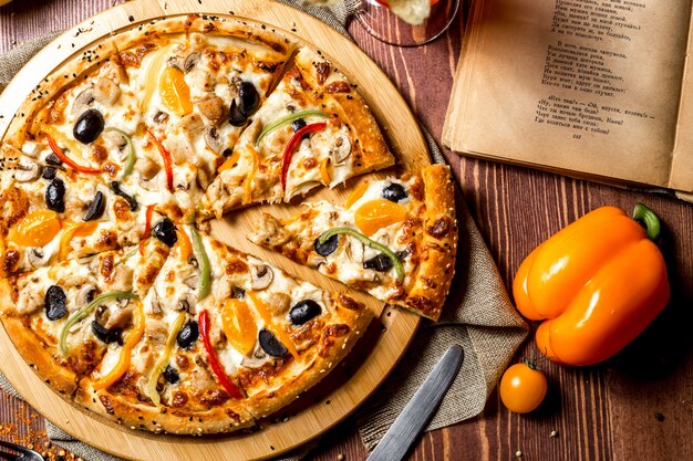 Top view chicken pizza with yellow cherry tomatoes and bell pepper on the board