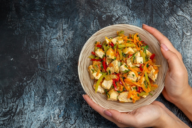 Top view of chicken salad with sliced vegetables on light surface