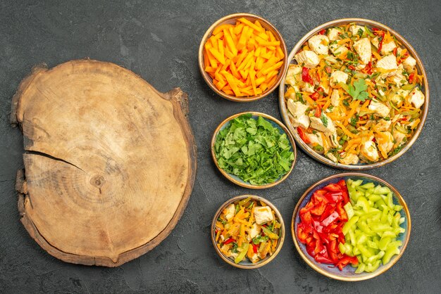 Top view chicken salad with vegetables and greens on a dark table diet salad health