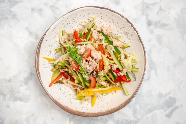 Top view of chicken salad with vegetables on stained white surface