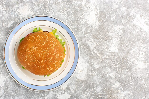 Top view of chicken sandwich with green salad and vegetables inside on white surface