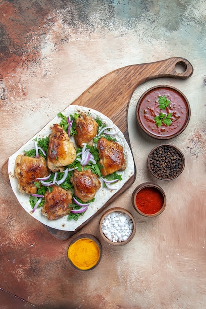 Free photo top view of chicken sauce colorful spices chicken with herbs on lavash on the board