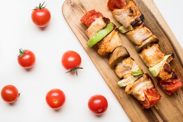 Top view chicken skewers on cutting board with cherry tomatoes