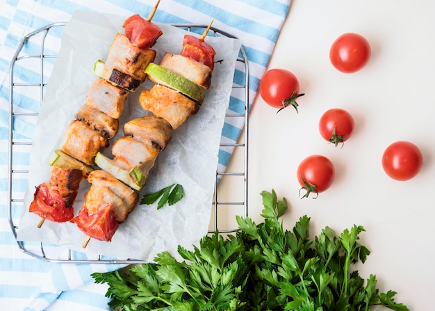 Top view chicken skewers on parchment paper with cherry tomatoes