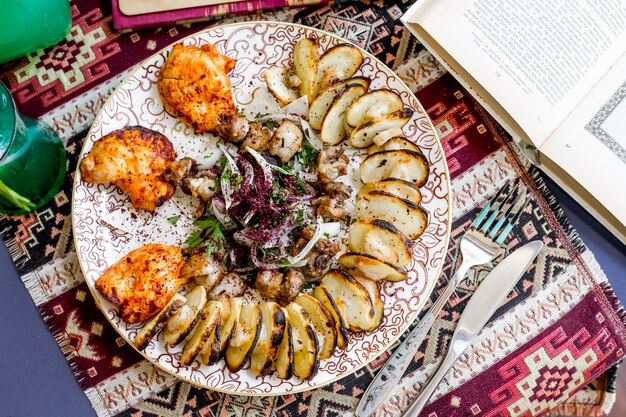 Top view chicken skewers with sliced potatoes onions and herbs sprinkled with sumac