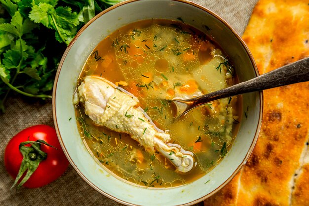 Top view chicken soup served with herbs tomato and bread