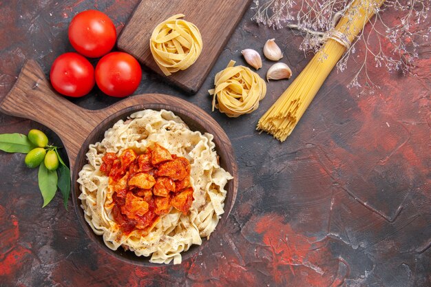 Top view chicken with dough pasta dish with tomatoes on dark surface pasta dough meal