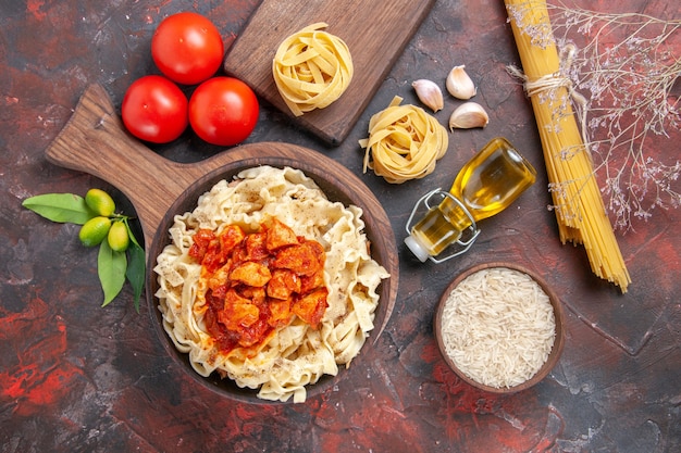 Top view chicken with dough pasta dish with tomatoes on dark surface pasta dough
