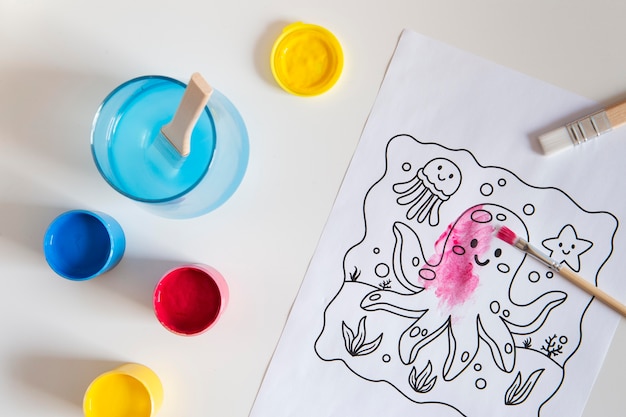 Вид сверху на детский стол с краской и рисунком